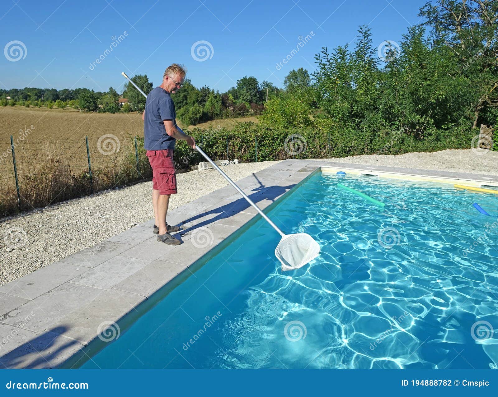 Persona limpiando una piscina con redes