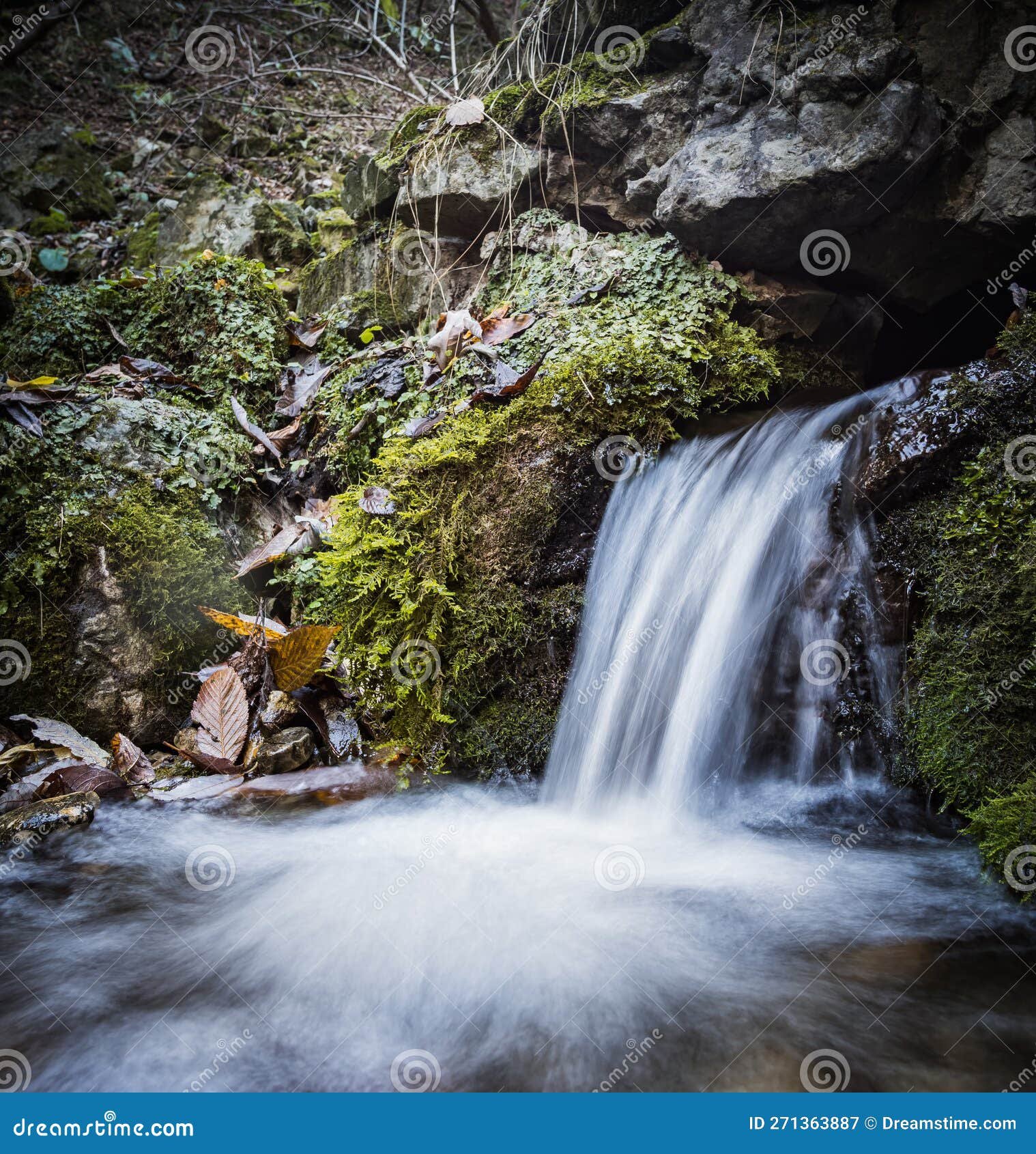 un manantial en las montanas con agua potable fluye de piedras como una pequena cascada fluida que rio larga exposicion 271363887