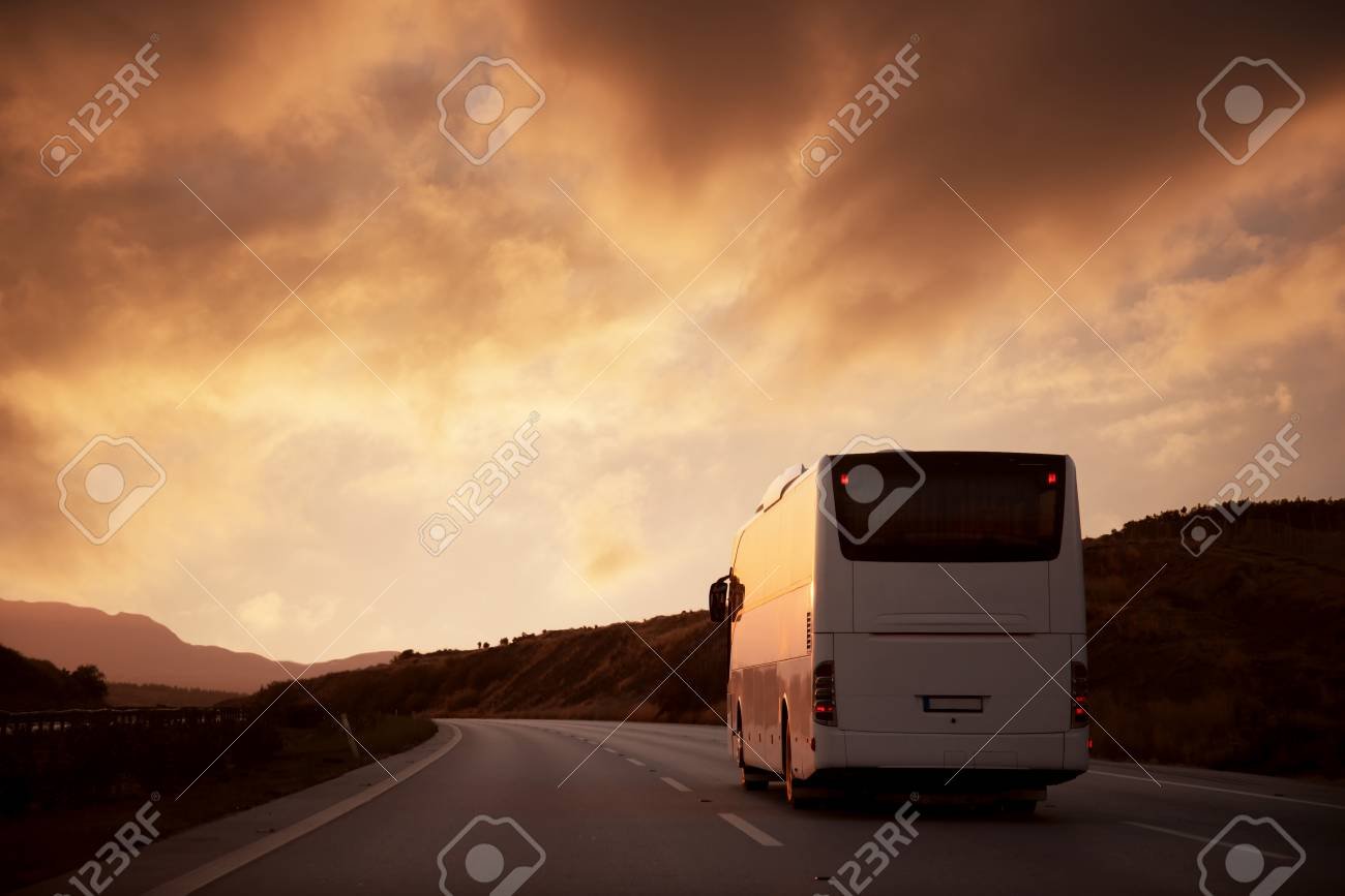 autobus viajando por carretera al atardecer